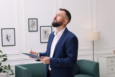 Photo of Real estate appraisal. Inspector with clipboard conducting property valuation indoors