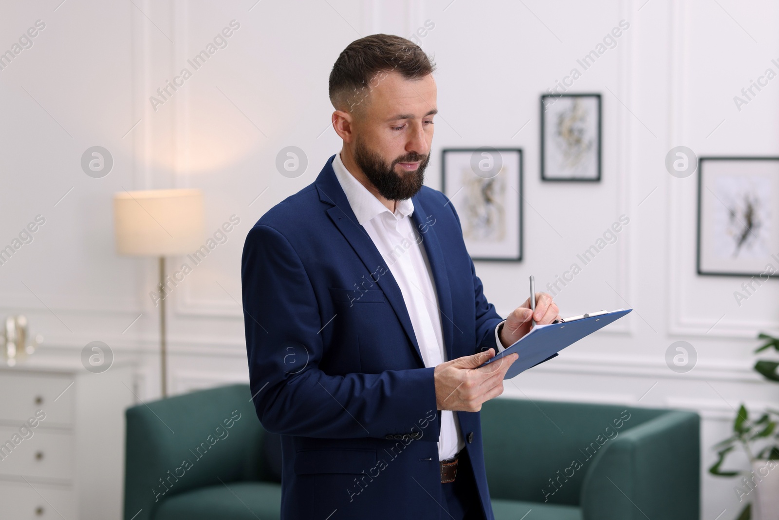 Photo of Real estate appraisal. Inspector with clipboard conducting property valuation indoors