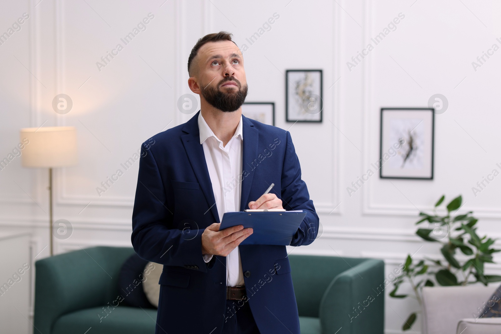 Photo of Real estate appraisal. Inspector with clipboard conducting property valuation indoors