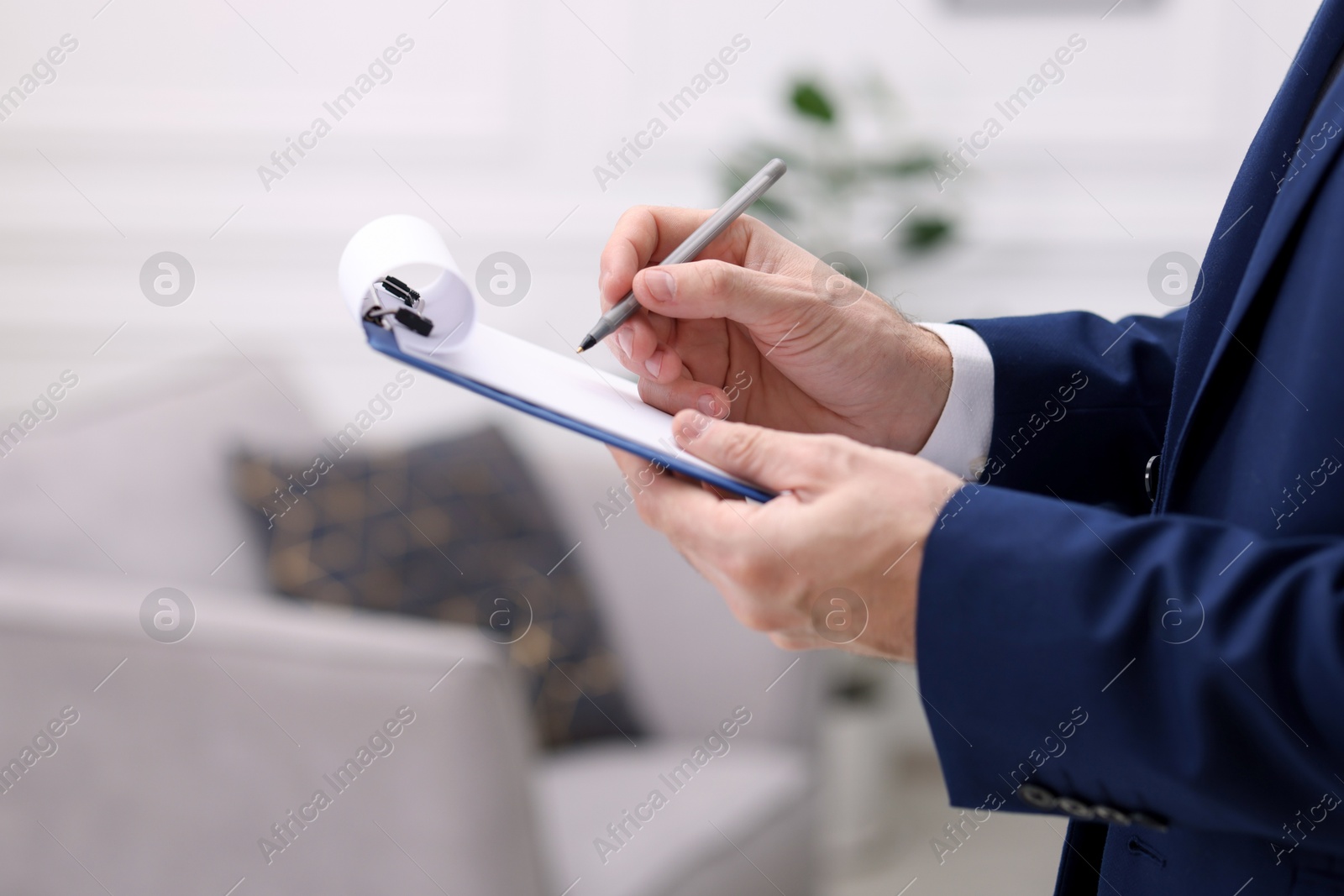 Photo of Real estate appraisal. Inspector with clipboard conducting property valuation indoors, closeup