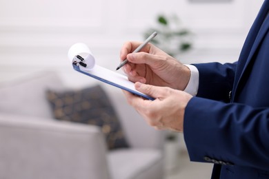 Photo of Real estate appraisal. Inspector with clipboard conducting property valuation indoors, closeup