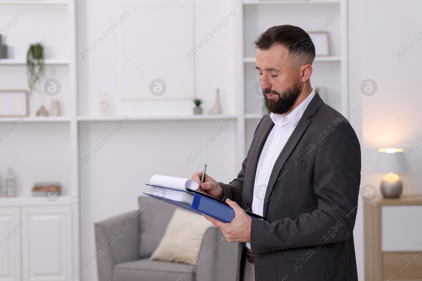 Photo of Real estate appraisal. Inspector with clipboard conducting property valuation indoors, space for text