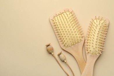 Photo of Wooden hair brushes and poppy heads on beige background, top view. Space for text