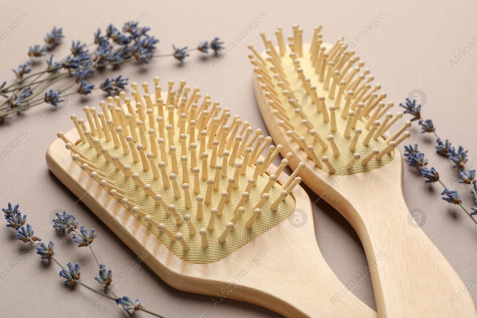 Photo of Wooden hair brushes and lavender flowers on color background, closeup