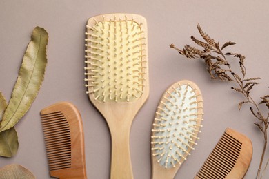 Photo of Wooden hair brushes, combs and plants on color background, flat lay