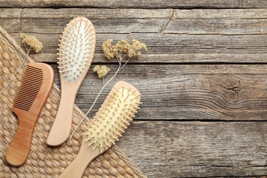 Photo of Hair brushes, comb and dried flowers on wooden background, flat lay. Space for text