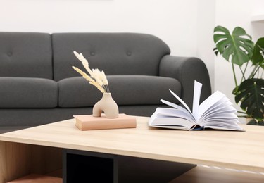 Photo of Coffee table with decor and book near sofa at home, closeup