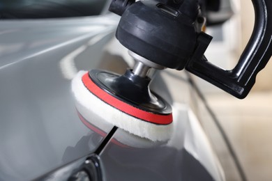 Photo of Man polishing car with orbital polisher indoors, closeup