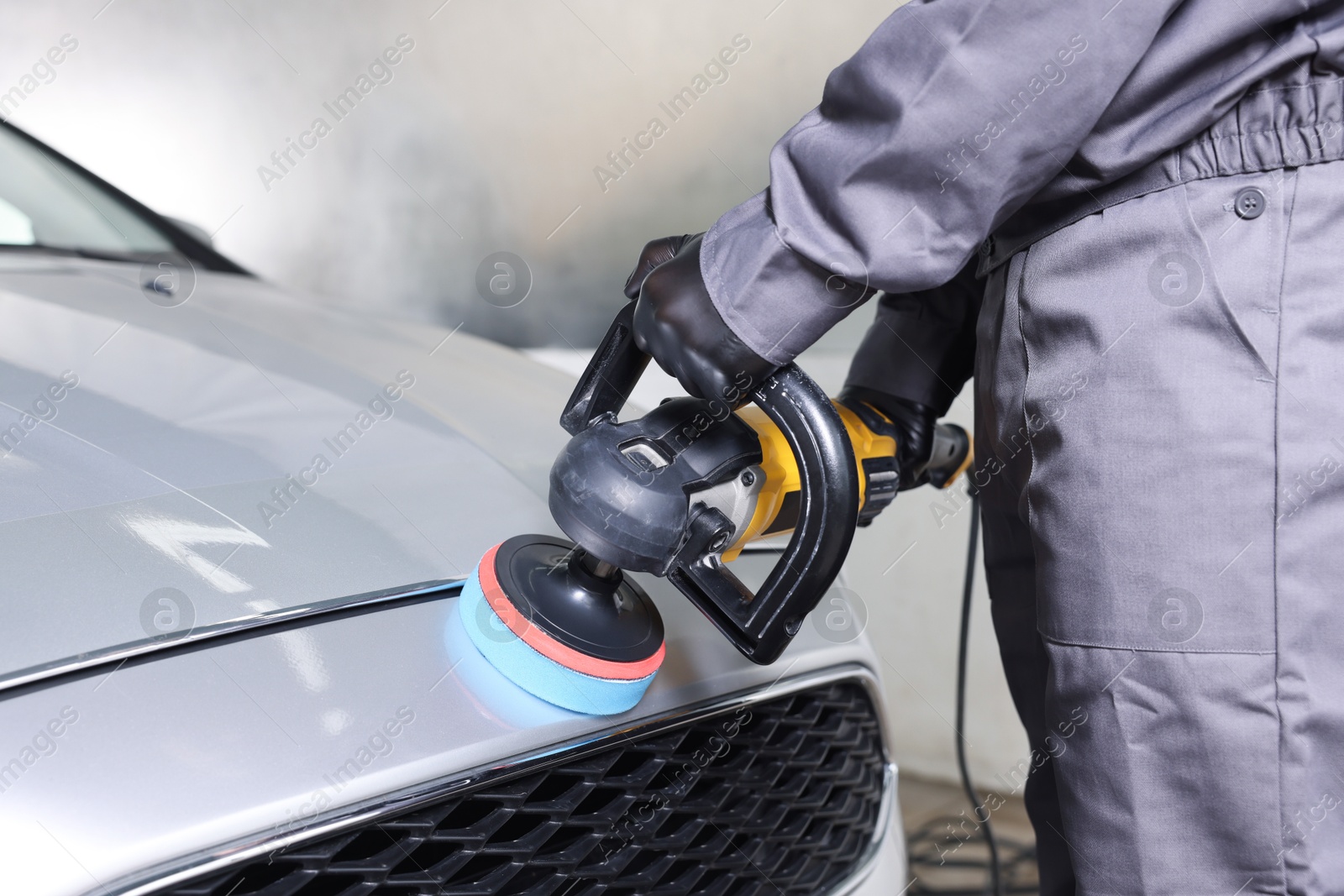 Photo of Man polishing car with orbital polisher indoors, closeup