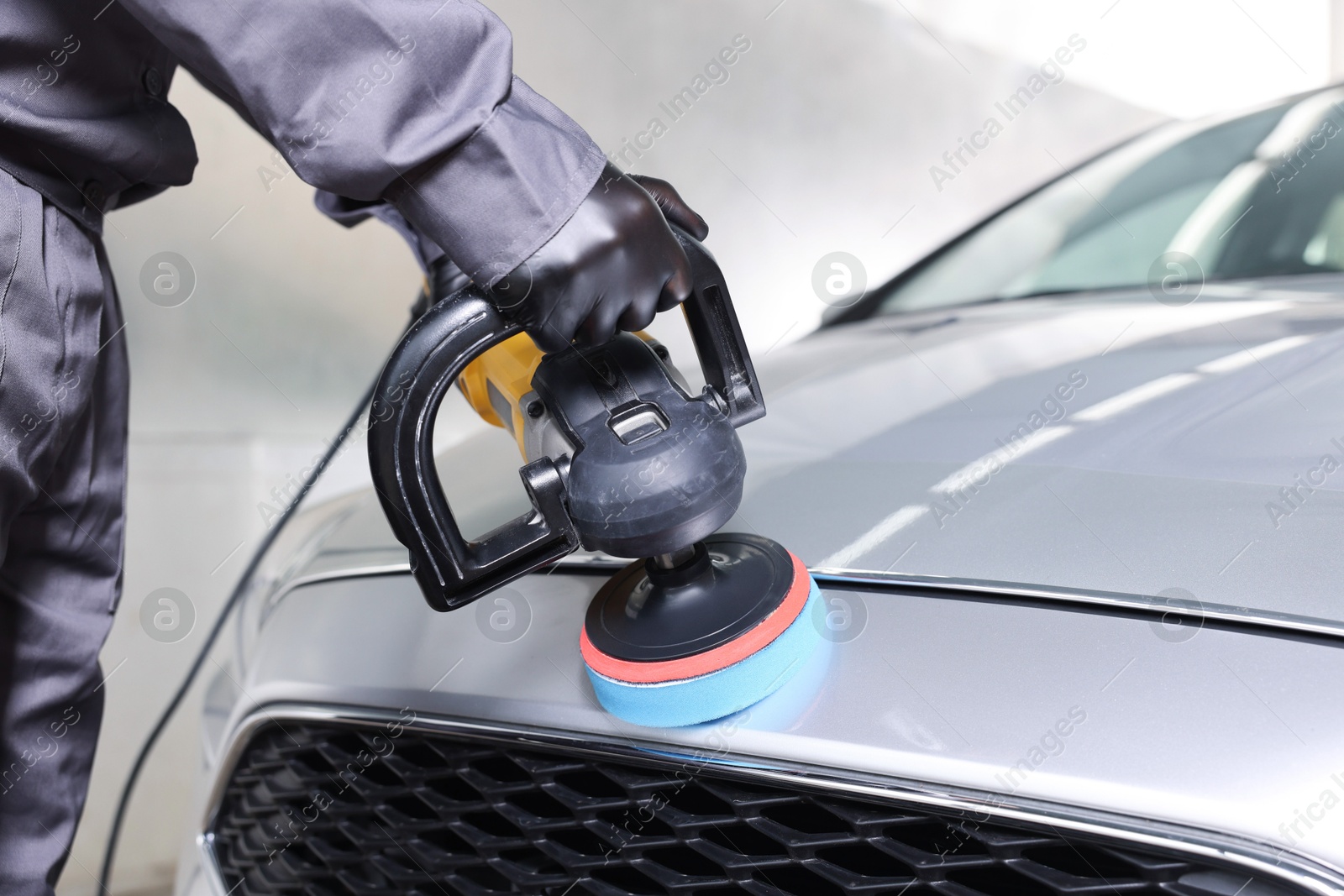 Photo of Man polishing car with orbital polisher indoors, closeup