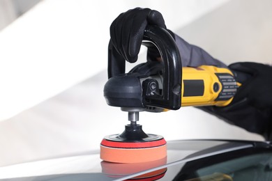 Photo of Man polishing car with orbital polisher indoors, closeup