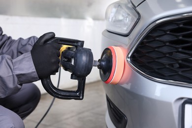 Photo of Man polishing car with orbital polisher indoors, closeup