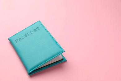 Photo of Passport in light blue cover on pink background, closeup. Space for text