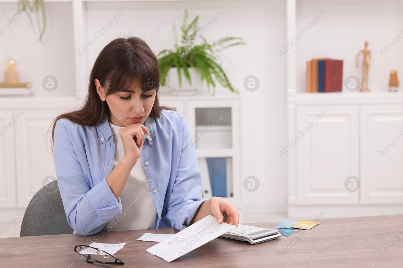 Photo of Paying bills. Woman with different invoices and calculator at wooden table indoors, space for text