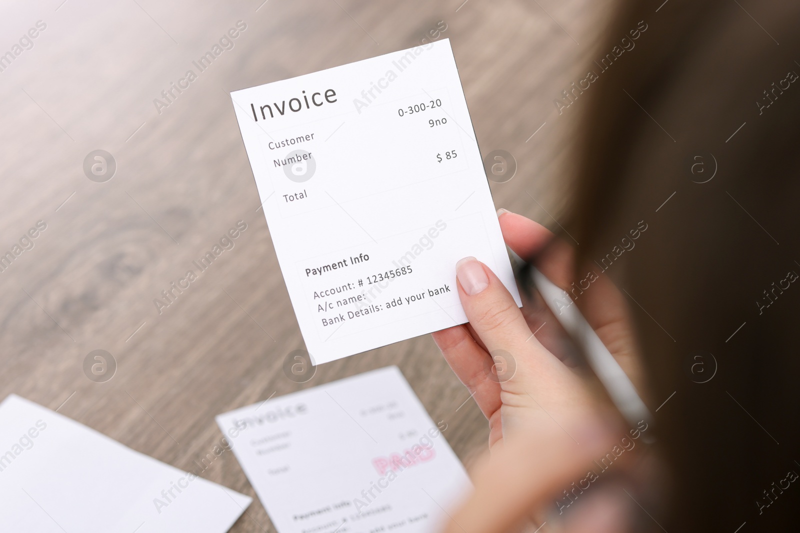 Photo of Paying bills. Woman with different invoices at wooden table indoors, closeup