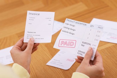 Photo of Paying bills. Woman with different invoices at wooden table indoors, closeup