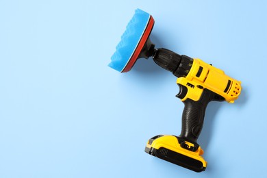 Photo of Electric screwdriver with polish pad on light blue background, top view. Space for text