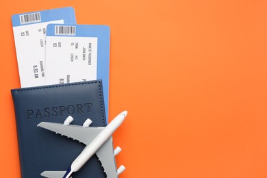 Photo of Travel agency. Flight tickets, passport and plane model on orange background, top view. Space for text