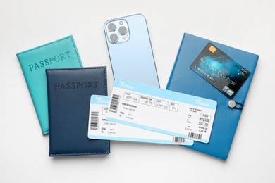 Photo of Travel agency. Flight tickets, passports, smartphone, notebook and credit card on light background, flat lay