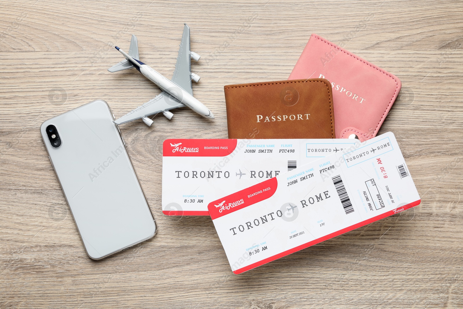 Photo of Travel agency. Flight tickets, passports, smartphone and plane model on wooden table, flat lay