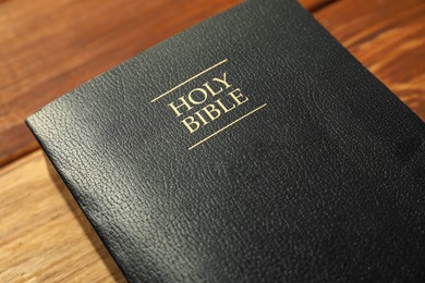 Photo of Hardcover Holy Bible in English language on wooden table, closeup