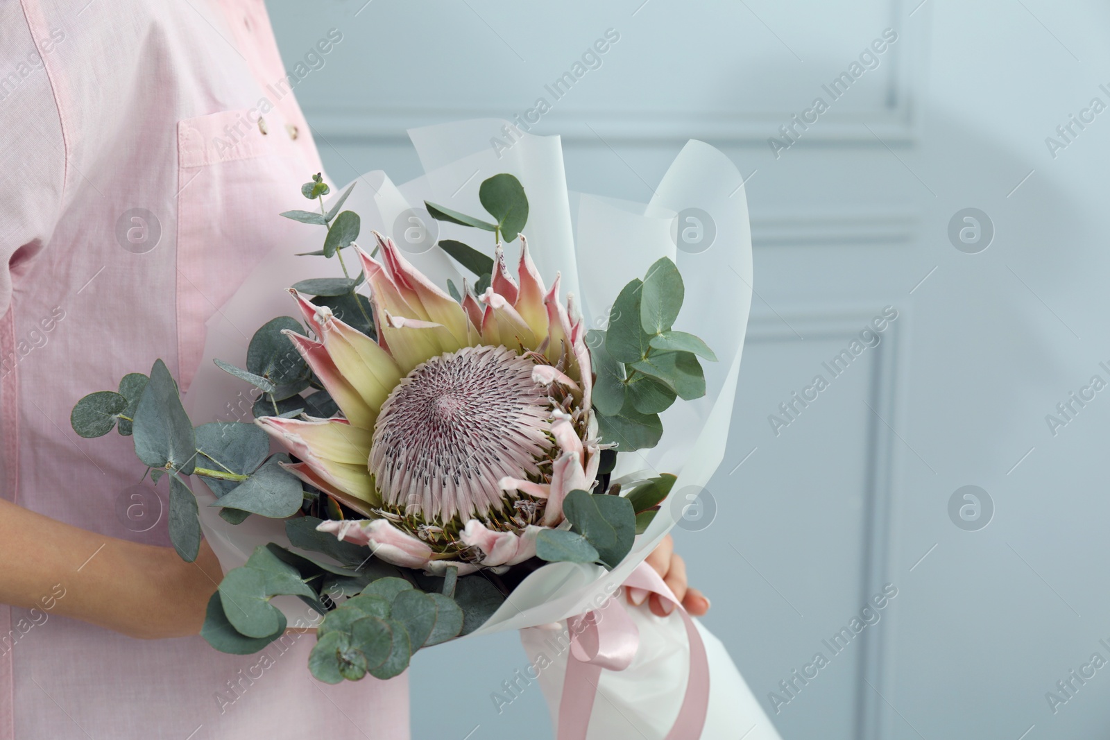 Photo of Woman with beautiful bouquet against light wall, closeup