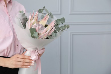 Photo of Woman with beautiful bouquet against light wall, closeup. Space for text