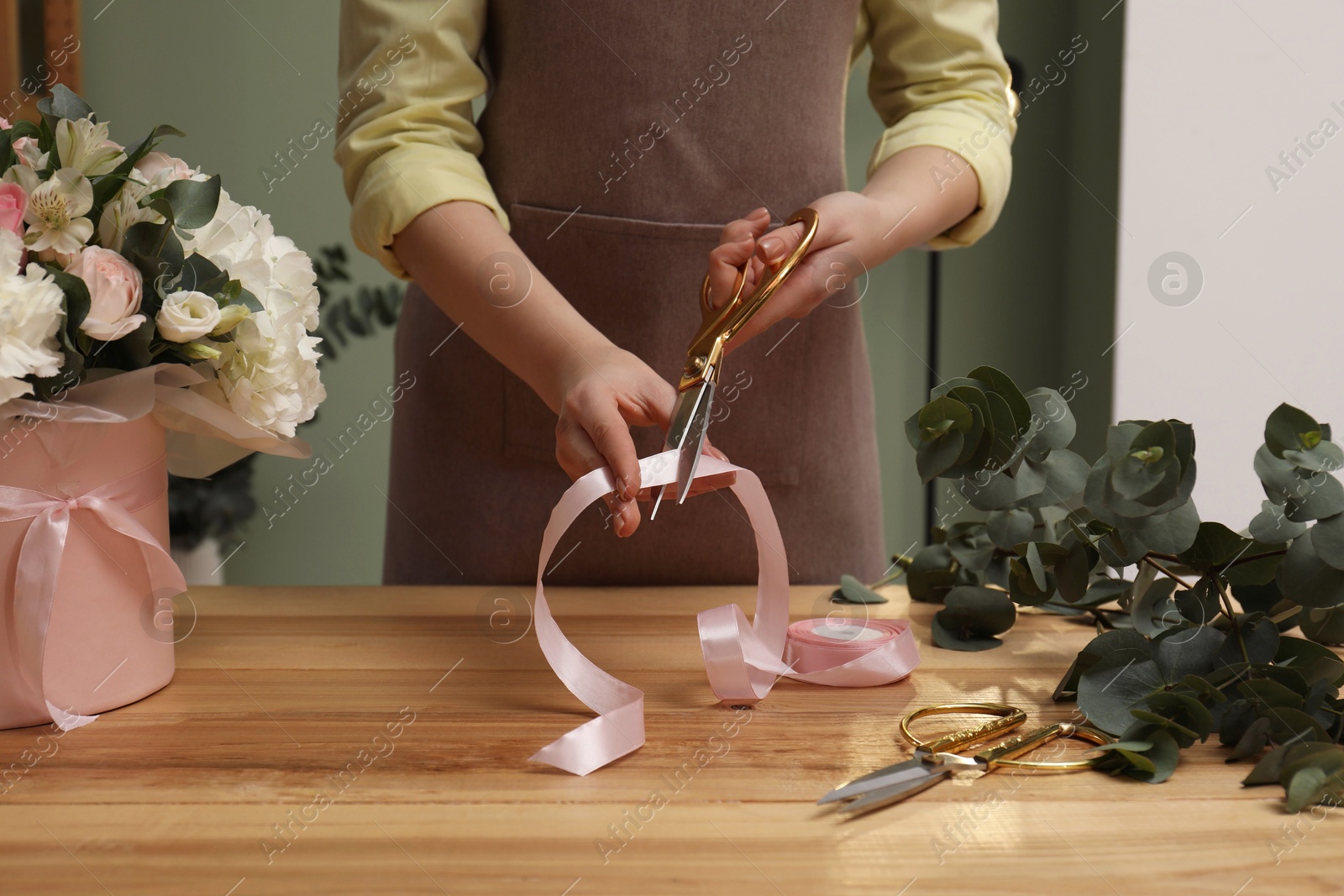 Photo of Florist making beautiful bouquet at table in flower shop, closeup