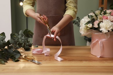 Photo of Florist making beautiful bouquet at table in flower shop, closeup