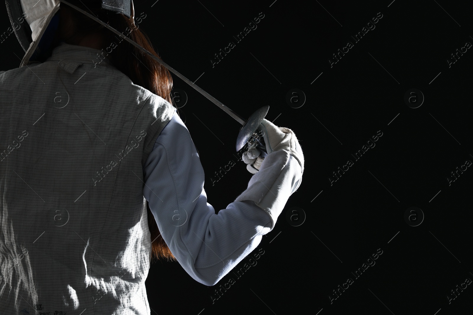 Photo of Fencer with epee on black background, back view. Space for text