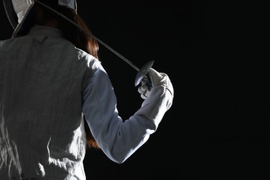 Photo of Fencer with epee on black background, back view. Space for text