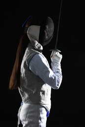 Photo of Fencer with epee on black background. Combat sport