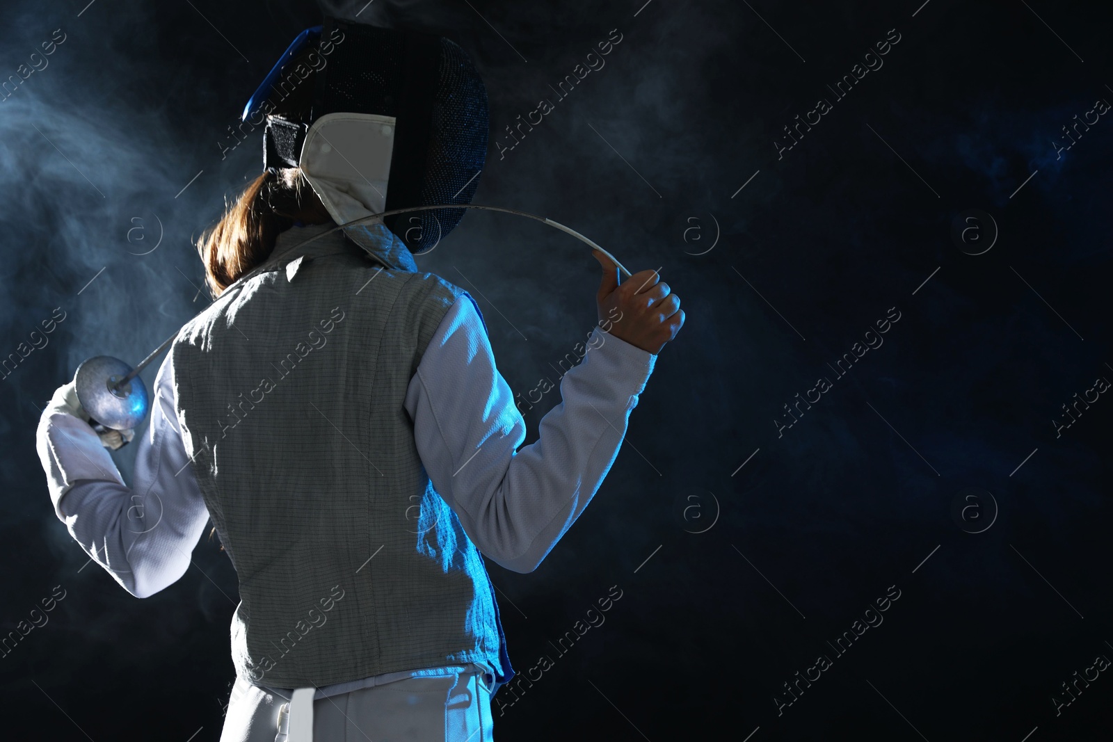 Photo of Fencer with epee in smoke on black background, space for text