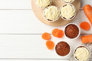 Photo of Tasty carrot muffins and fresh vegetables on white wooden table, flat lay. Space for text