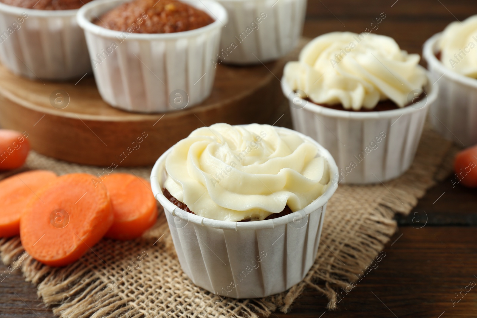 Photo of Tasty carrot muffins and fresh vegetable on wooden table, closeup