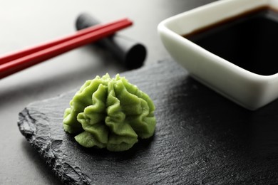 Photo of Hot wasabi paste, soy sauce and chopsticks on grey table, closeup