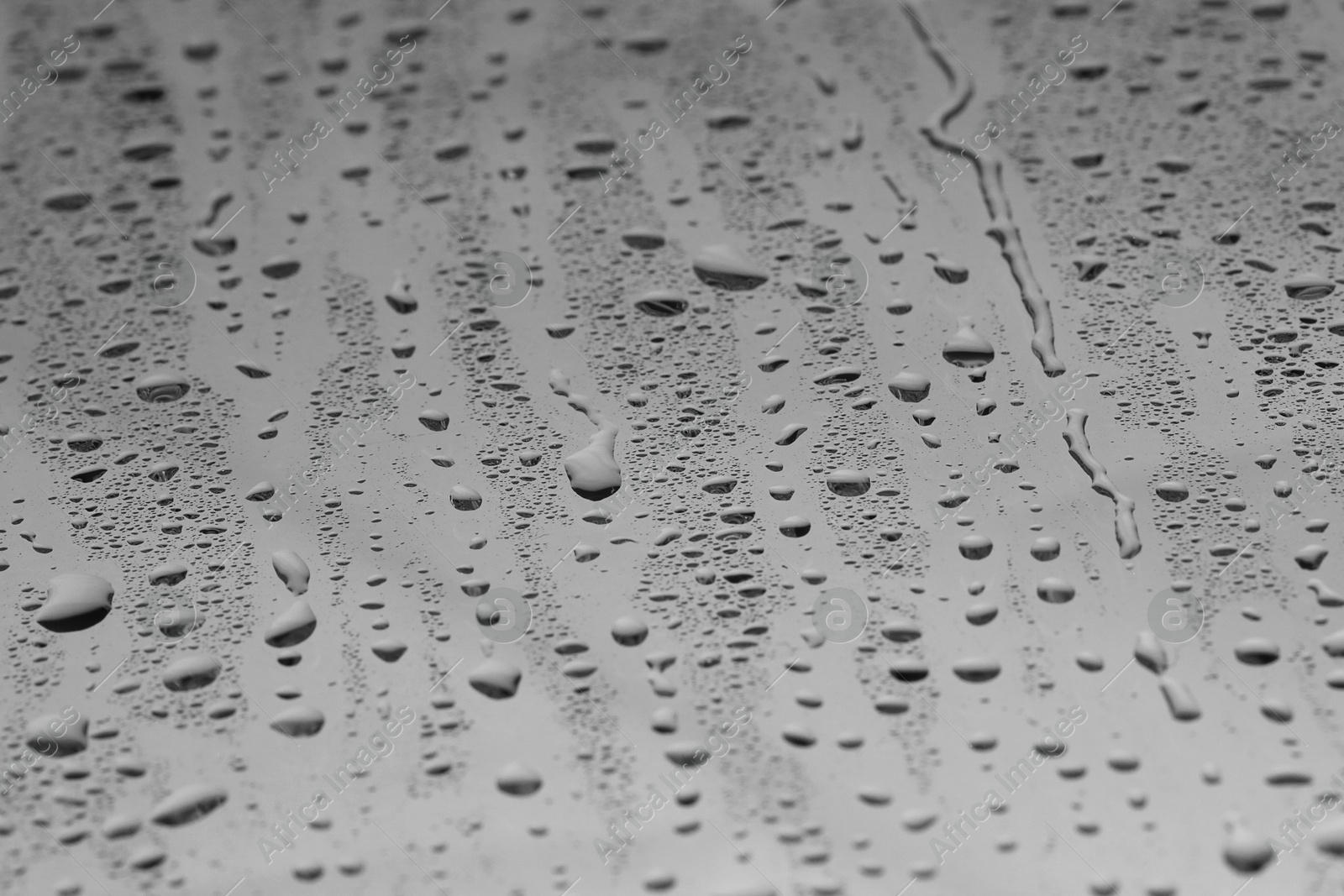 Photo of Water drops on grey glass surface, closeup