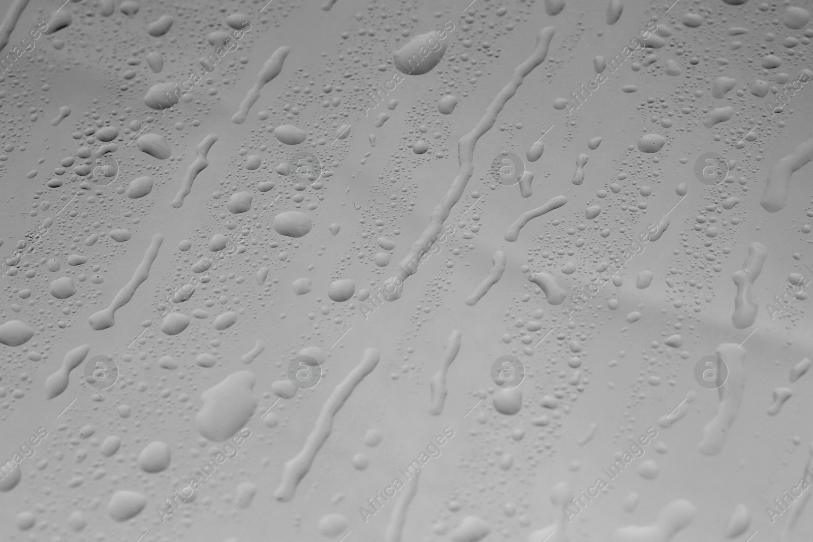 Photo of Water drops on grey glass surface, closeup