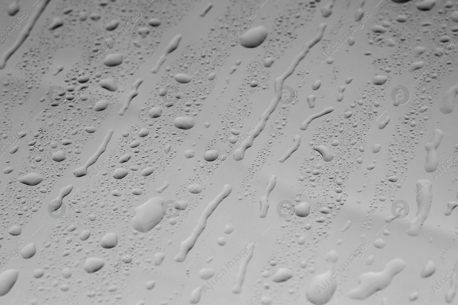 Photo of Water drops on grey glass surface, closeup