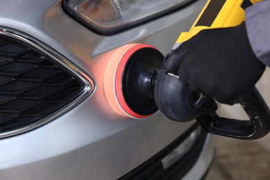 Photo of Man polishing car with orbital polisher indoors, closeup