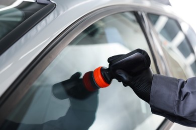 Photo of Man polishing car window indoors, closeup view