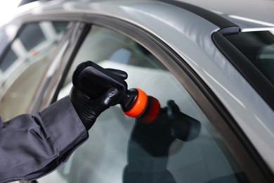 Photo of Man polishing car window indoors, closeup view