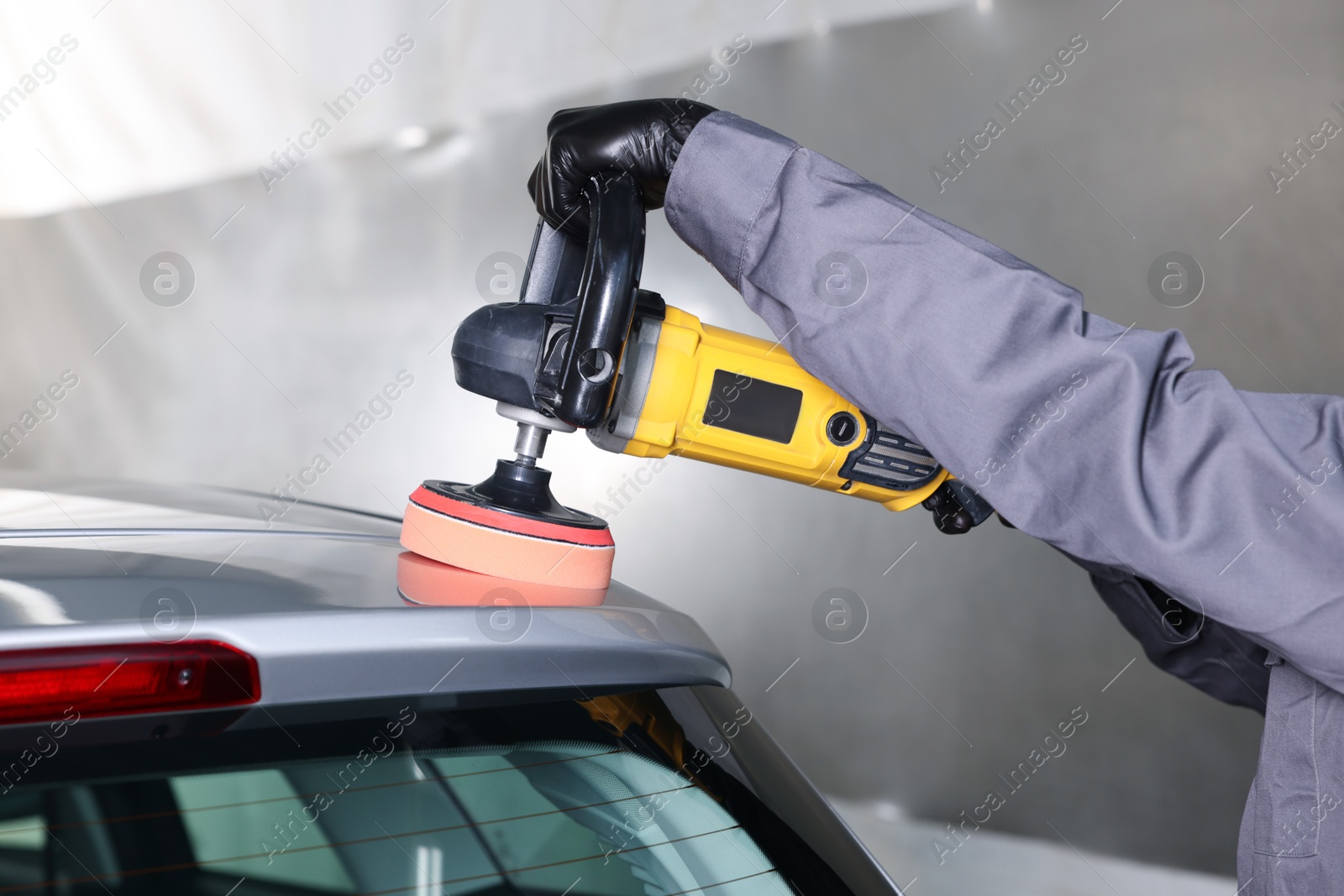 Photo of Man polishing car with orbital polisher indoors, closeup