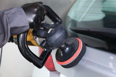 Photo of Man polishing car with orbital polisher indoors, closeup