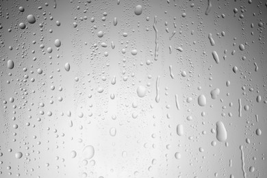 Photo of Water drops on light grey glass surface, top view