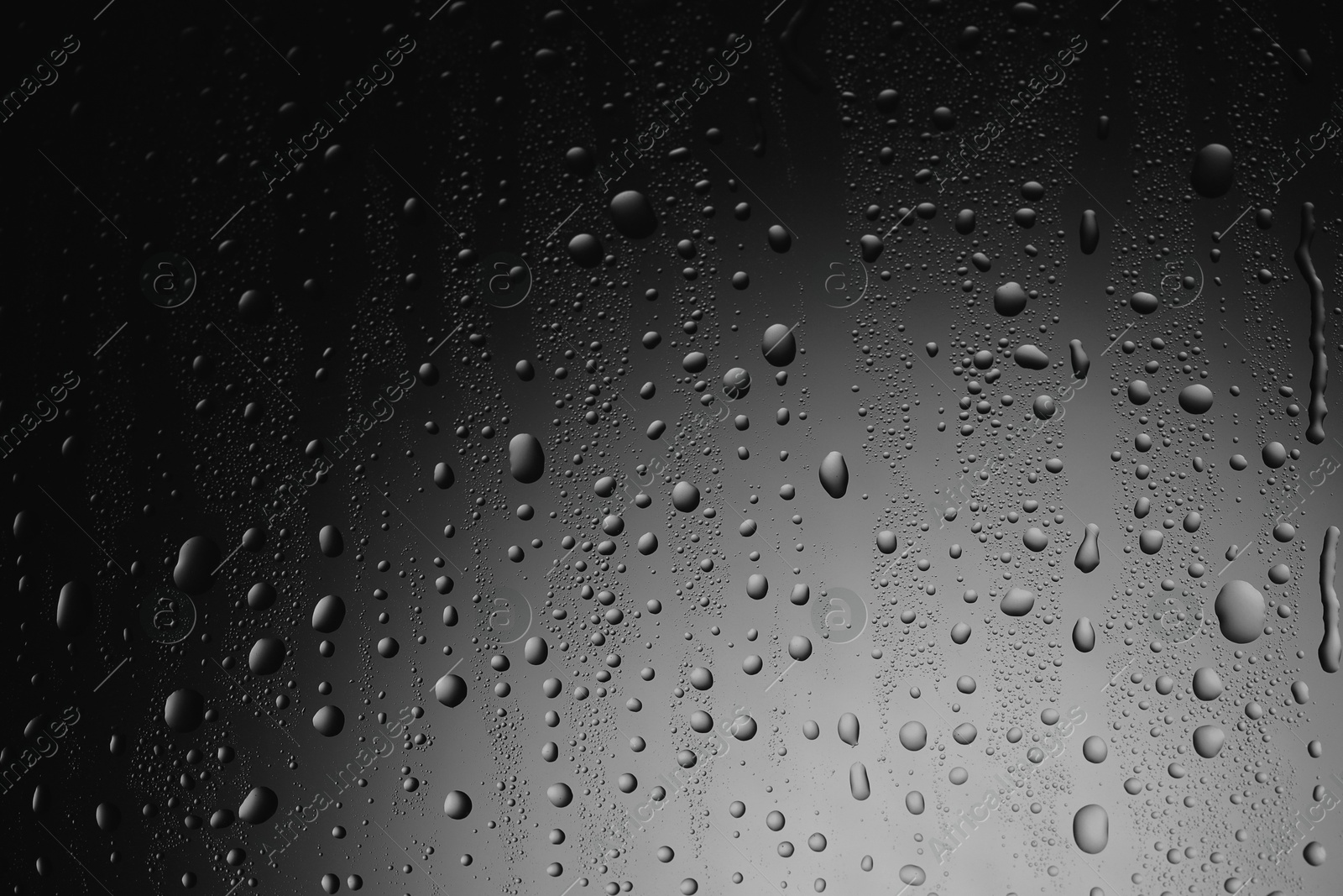 Photo of Water drops on dark grey glass surface, top view