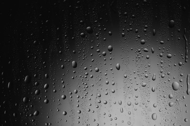 Photo of Water drops on dark grey glass surface, top view