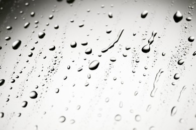 Water drops on light grey glass surface, closeup