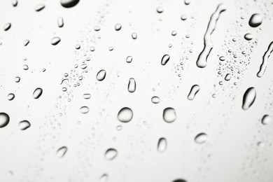 Water drops on light grey glass surface, closeup