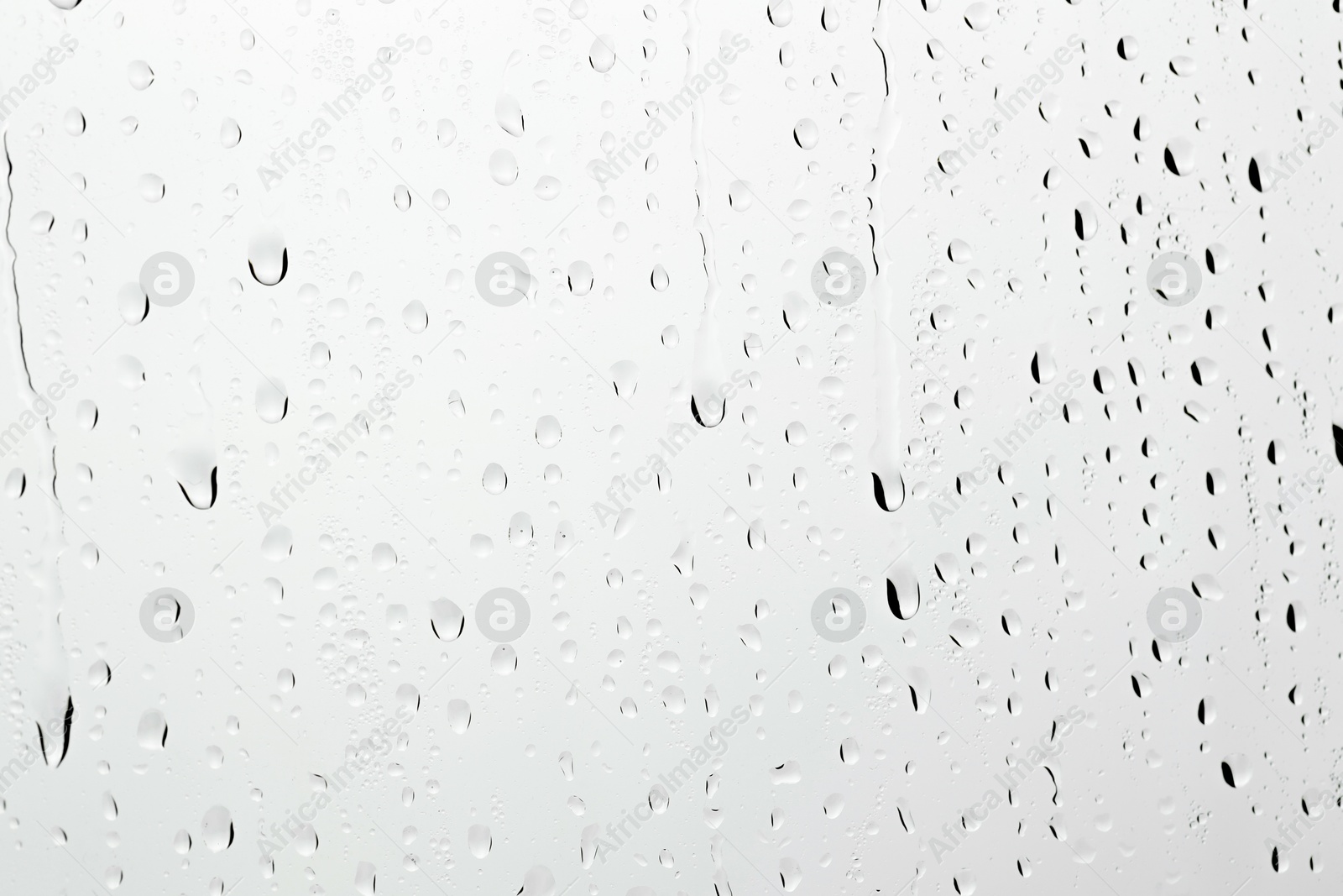 Photo of Water drops on light grey glass surface, closeup